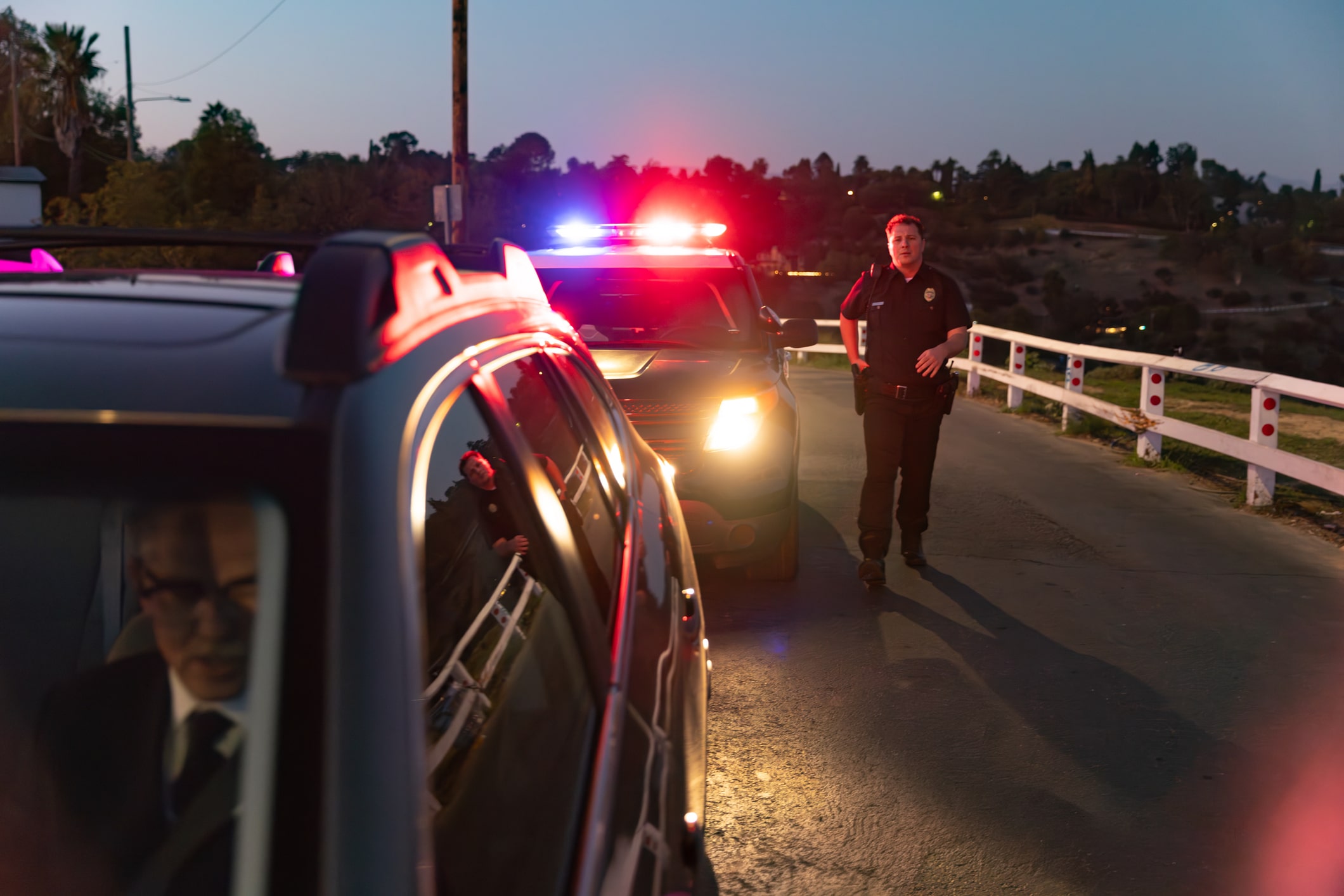 Police officer approaching a driver's window during a nighttime traffic stop for suspected aggravated DWI